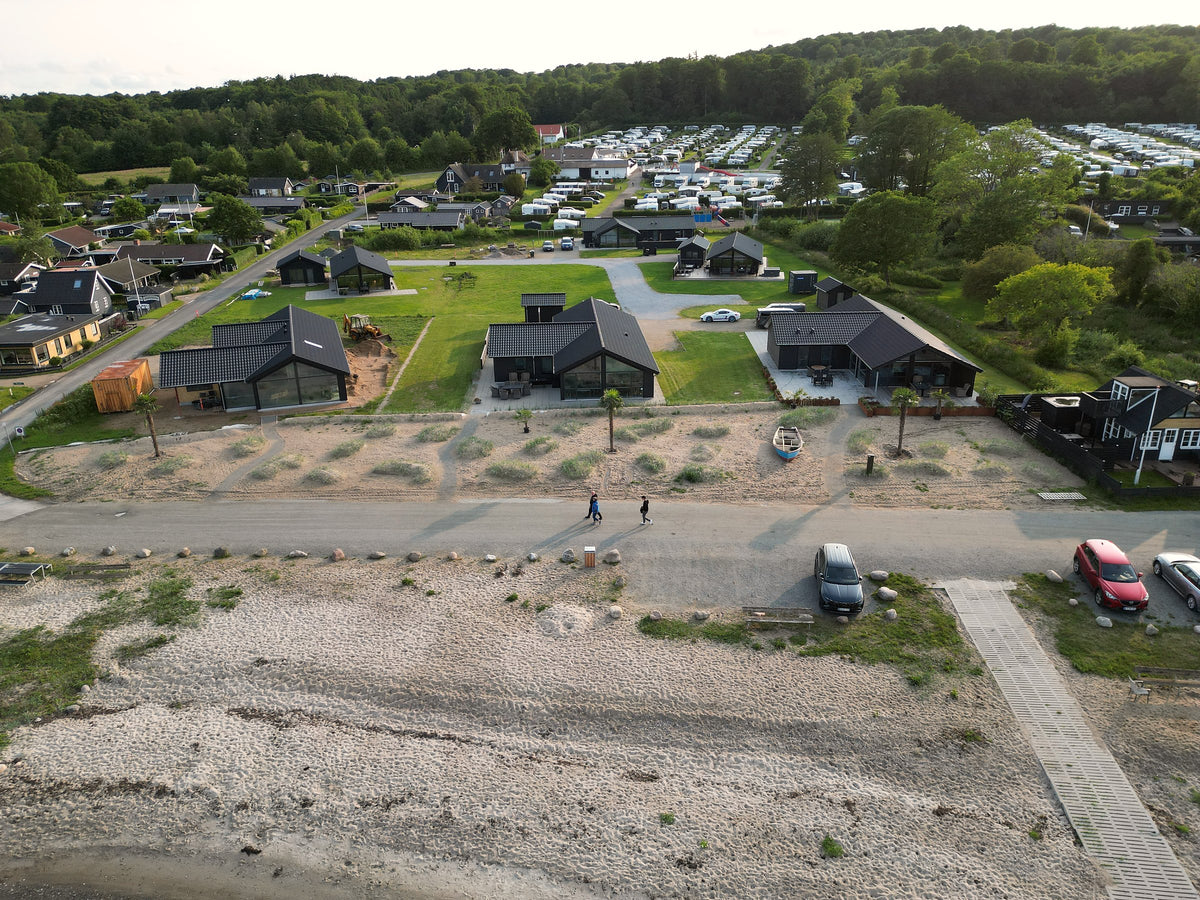 Dronefoto af nye feriehuse ved stranden med plantede hørpalmer